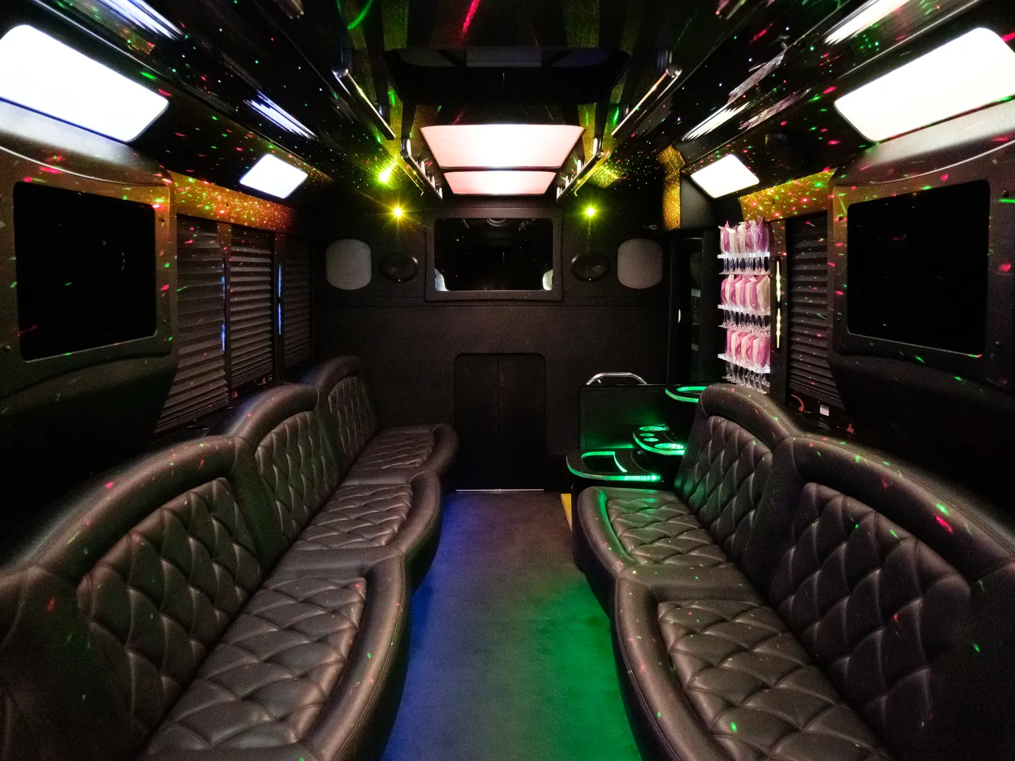 Inside a BAC party bus: quilted leather lounge seating, a lit bar and multicolor ceiling lights