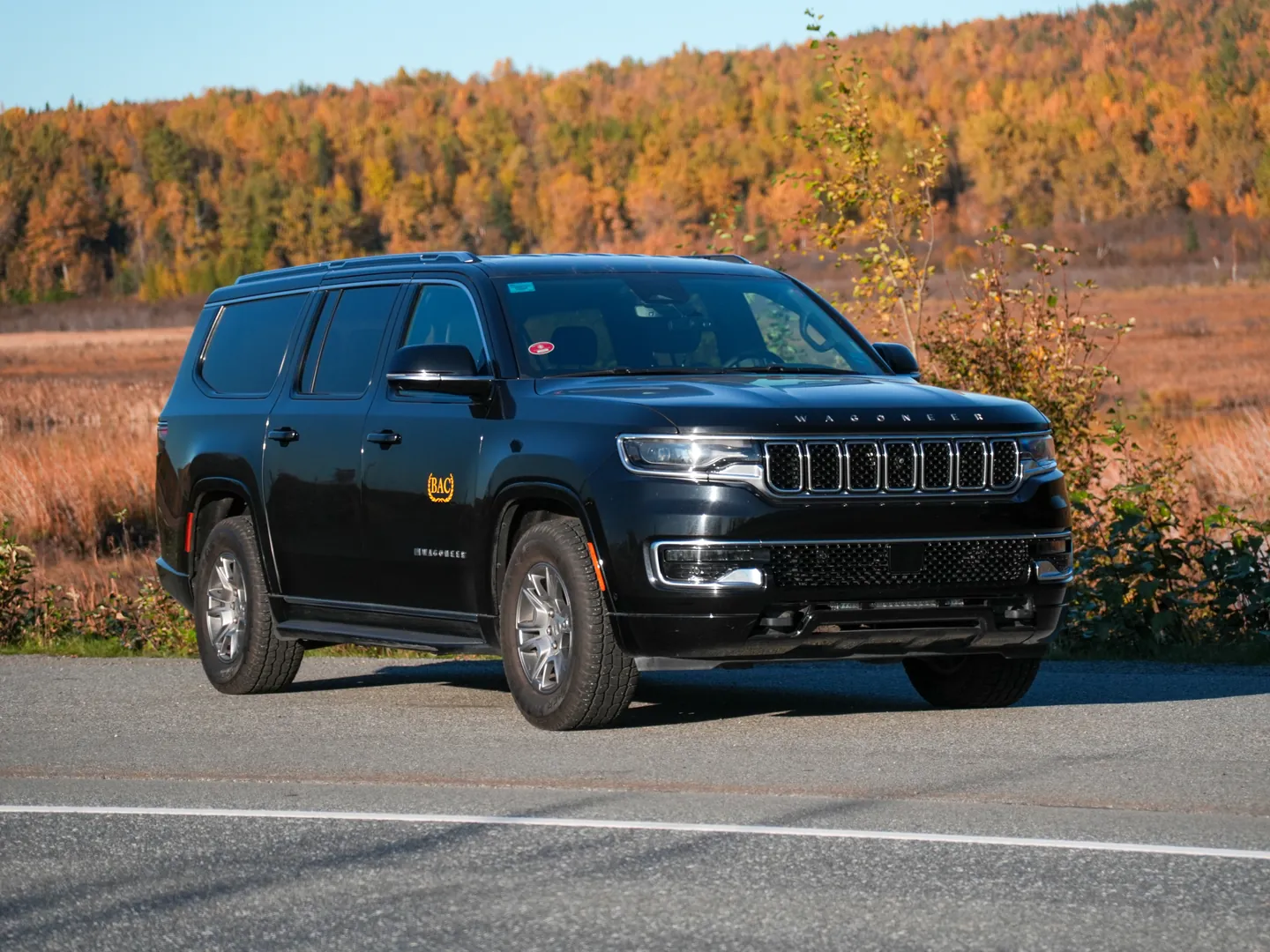 BAC's black Jeep Wagoneer on an Alaska road in fall, golden birch and marsh behind